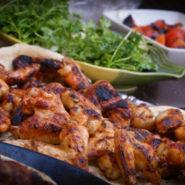 A close-up of grilled chicken wings served with fresh herbs and vegetables, perfect for culinary presentations.